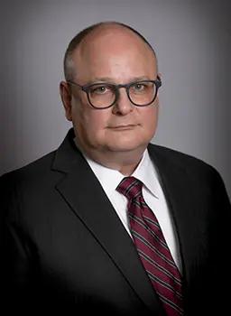 Man wears suit and tie for a headshot.