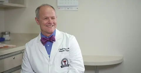 Jerry Grimes, M.D. smiling in a white coat