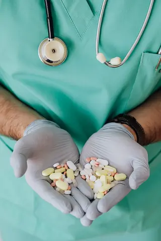 medical gloved hands holding an assortment of medication
