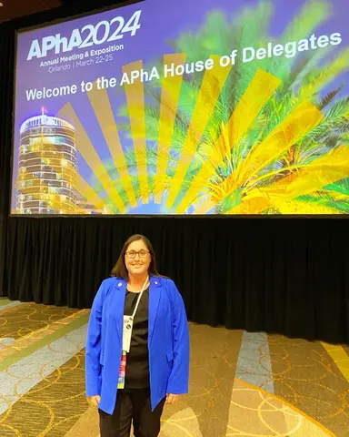 Mary S. Klein, Pharm.D., standing in front of a colorful backdrop