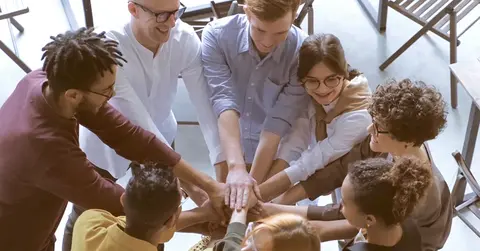 people putting their hands together in team building