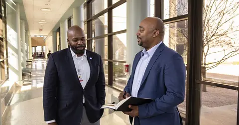two health care professionals talking in a hallway
