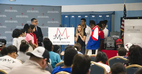 TTUHSC school of medicine team standing near a poster board for middle school to medical school initiative 