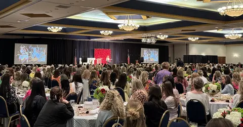 room full of people listening to speaker on a stage