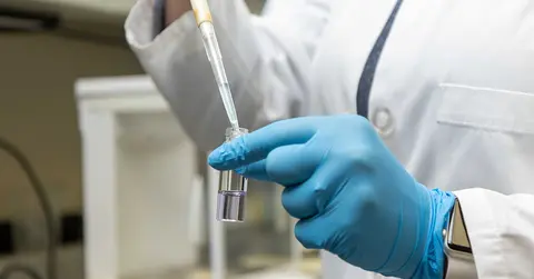 close up of gloved hands performing research in a lab