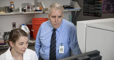 Dr. Reynolds looking at a computer with a member of his team