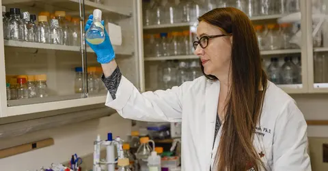 Kendra Rumbaugh, Ph.D., looking at laboratory equipment