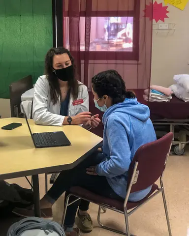 student with mentor at table with laptops