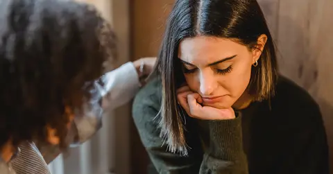Woman looking sad as someone comforts her