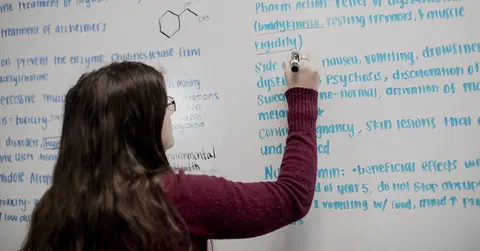 student writing on dry erase board
