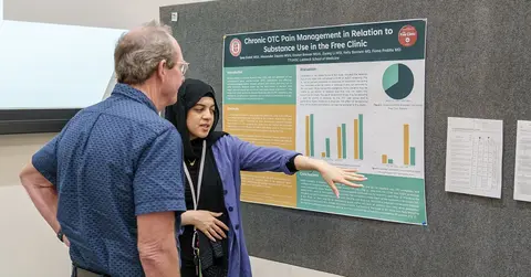 student giving poster presentation for student research week 