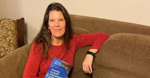 Julie St. John sitting with her textbook on Community Health Workers