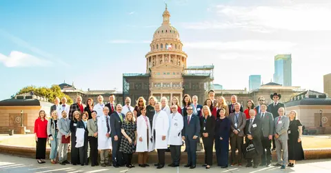 Large group TTUHSC faculty and staff stand in front of the State Capitol of Texas building.