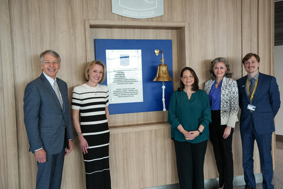 CPRIT members touring Cancer Center standing in front of bell